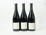 trois bouteilles de vin sont alignées sur une surface blanche
