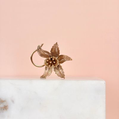 la bague en forme de fleur dorée repose sur un bloc de marbre blanc