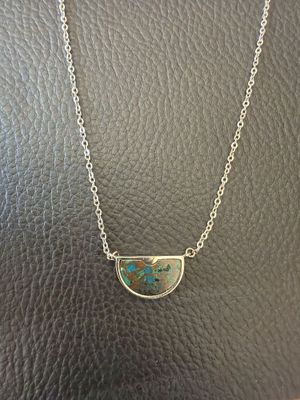 a silver necklace with a turquoise stone in the shape of a half circle