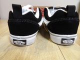 a pair of black and white vans sneakers on a table