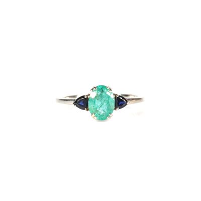 un gros plan d'une bague sertie d'une émeraude verte et d'un saphir bleu