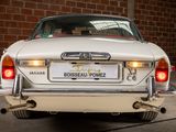 a white car parked in front of a brick wall