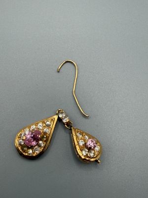 paire de boucles d'oreilles ornées de pierres roses et blanches sur un fond gris