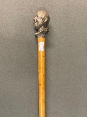 une image représentant un bâton en bois surmonté d'une tête en bronze