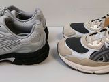 deux paires de baskets blanches et grises posées sur une surface blanche