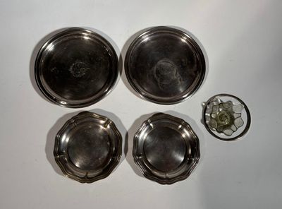 four silver dishes and a glass on a white surface