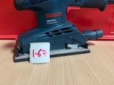 La ponceuse orbitale Bosch est posée sur une table, à côté d'une boîte rouge.