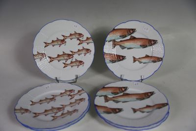 quatre assiettes ornées de poissons, posées sur une table