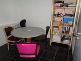 a table and chairs in a small room with a bookcase