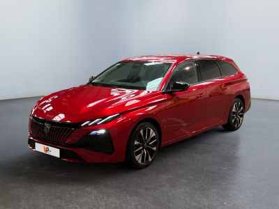 Une voiture rouge est garée dans une pièce aux murs blancs.