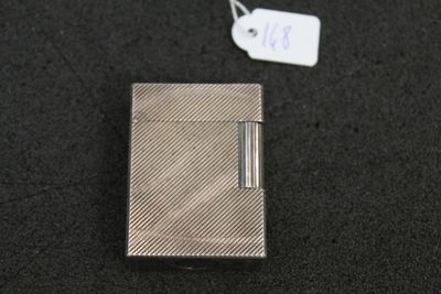 a silver cigarette case sitting on a black surface next to a tag
