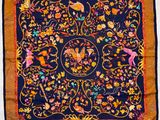 un gros plan sur une écharpe noire et orange ornée d'oiseaux et de fleurs