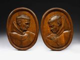 a pair of carved wood plaques depicting a man and a woman