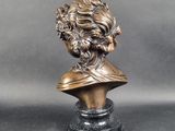 a bronze bust of a man with long hair on a marble base