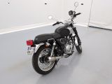 a black motorcycle parked in a room with a white wall