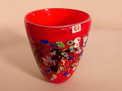 a red vase that has a lot of stickers on it