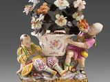 deux figurines d'enfants assis sur une table avec un panier de fleurs