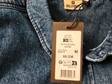 the back of a blue jean jacket with a price tag on it