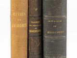 trois vieux livres posés l'un sur l'autre sur une surface blanche