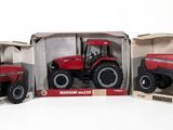three red toy tractors in boxes on a white surface