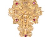 un gros plan d'une croix en or ornée de pierres rouges