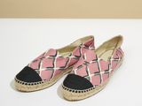 une paire d'espadrilles roses et noires posées sur une surface blanche