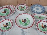 de nombreuses assiettes et bols décorés de coqs, posés sur une table
