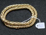 gros plan d'un bracelet en or sur une surface noire