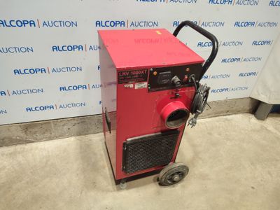 a red machine sitting on top of a cement floor next to a wall