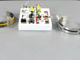 quatre bracelets différents posés sur une table, à côté d'une boîte blanche