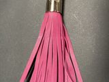 a close up of a pink tassel on a black surface