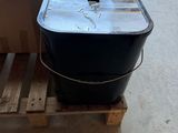 a black bucket sitting on top of a pallet in a room