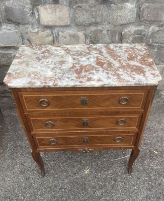 an old dresser with a marble top sits in front of a brick wall