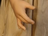 a close up of a doll ' s hand with a dress on