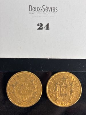 two gold coins are sitting on a black surface next to a white box