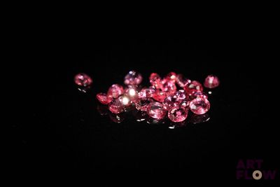 some pink diamonds on a black surface in the dark