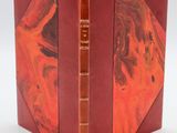 un livre ouvert à couverture rouge posé sur une table blanche