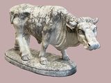 statue d'un taureau posée sur un socle en pierre, sur fond rose