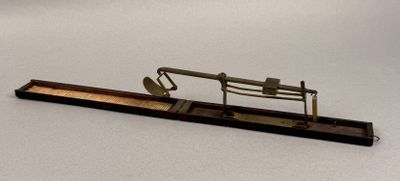 a small metal object on a wooden stand on a white surface
