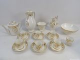 a white and gold tea set on a white table
