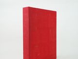 the red book is sitting on a white surface with a white background