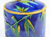 a blue and yellow container with a bamboo handle on it