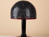 a black lamp with a red base on a white table