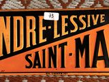 une affiche accrochée au mur sur laquelle on peut lire « Gendre Lessive Saint-Marc »