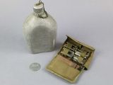 a small white bottle with a metal latch next to a coin