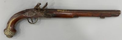un vieux pistolet avec une poignée en bois sur une surface blanche