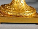 a gold clock on a stand on a table