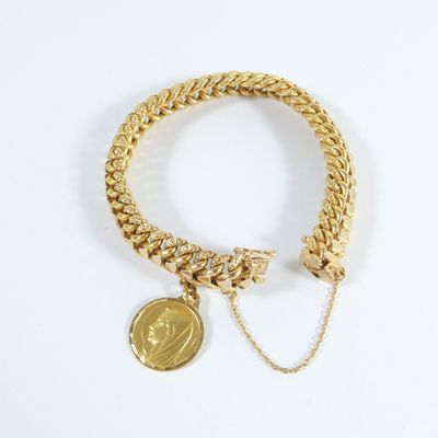 Gros plan sur un bracelet en or orné d'une pièce de monnaie