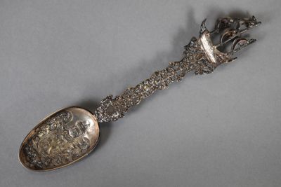 une cuillère en argent avec un manche en métal posée sur une table