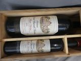 two bottles of wine in a wooden box on a bed